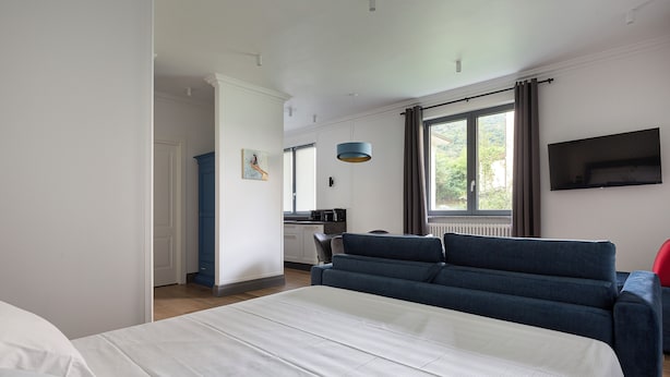 Habitación de hotel moderna con una cama grande, un sofá, un televisor y vistas al exterior.