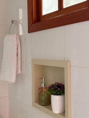Une salle de bain équipée d’un porte-serviettes sur lequel sont posées deux serviettes, d’un distributeur de savon et d’une plante en pot.