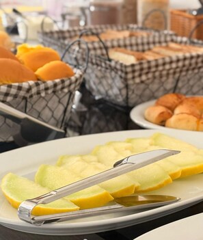 Un buffet de petit-déjeuner proposant une variété d’aliments, notamment des fruits coupés et des viennoiseries.