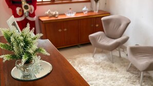 Een kamer met een houten tafel, een decoratieve plant, een klein beeldje en een kerstfiguur. Op de achtergrond staan twee stoelen en een kast.