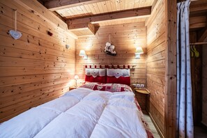 Ein Holzhütten-Zimmer mit einem Bett, Wandlampen und einem hängenden Schuhregal.