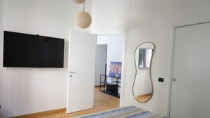 Quarto com uma cama, televisão, porta e espelho.