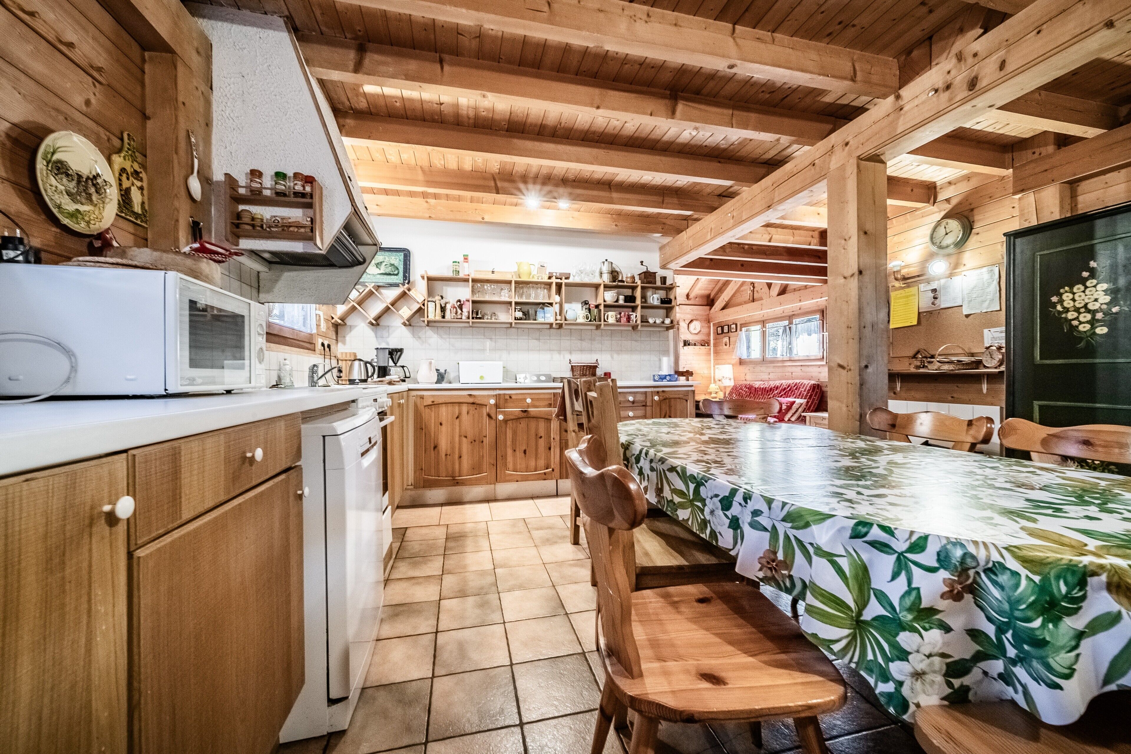 A wooden cabin interior with a kitchen, dining area, and a bed.