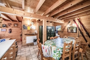 Ein Holzblockhaus-Innenraum mit Essbereich, Küche und einem Skiständer.