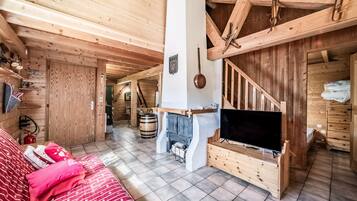 Un interior de madera con chimenea, televisor y sofá.