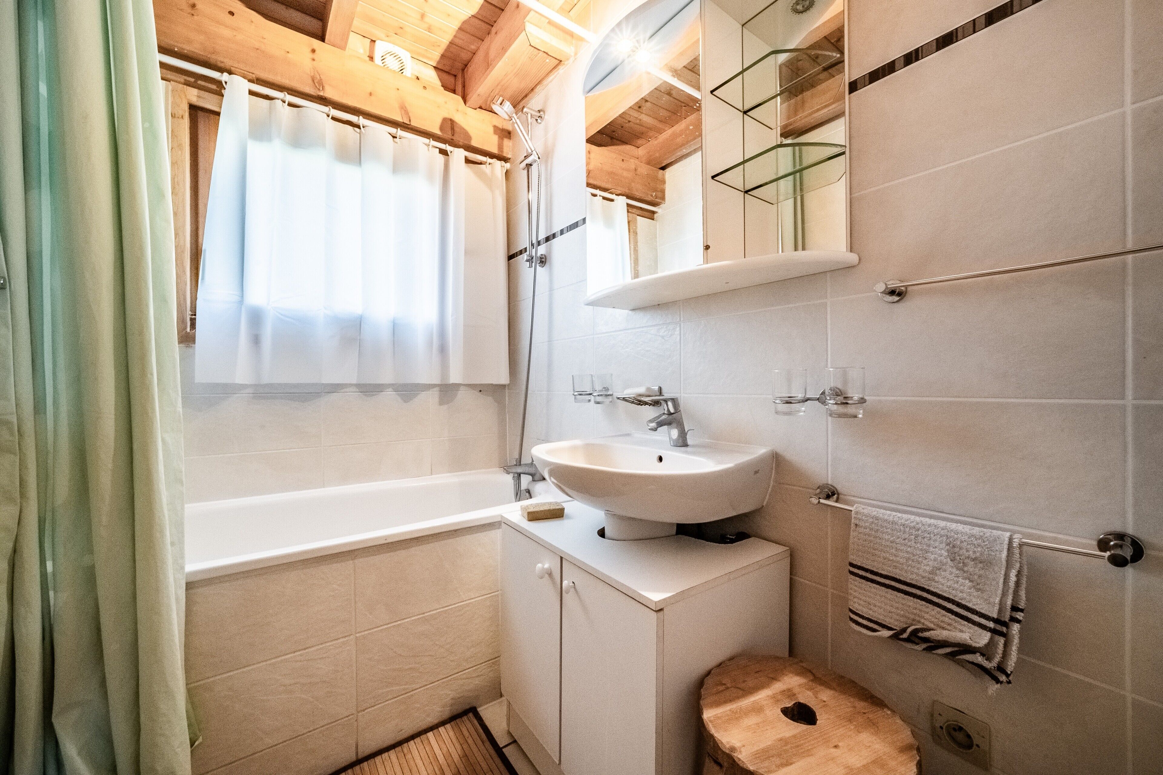 Un baño con bañera, lavamanos, espejo y perchero para toallas.