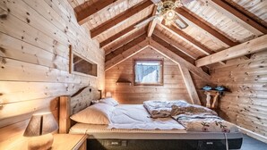A wooden cabin bedroom with a loft bed, a window, and a ceiling fan. - Chalet “8p Simple - Les Mésanges” with Mountain View, Private Terrace, and Wi-Fi (Verchaix)