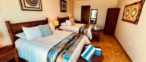 A hotel room with two beds, a ceiling fan, and artwork on the walls.