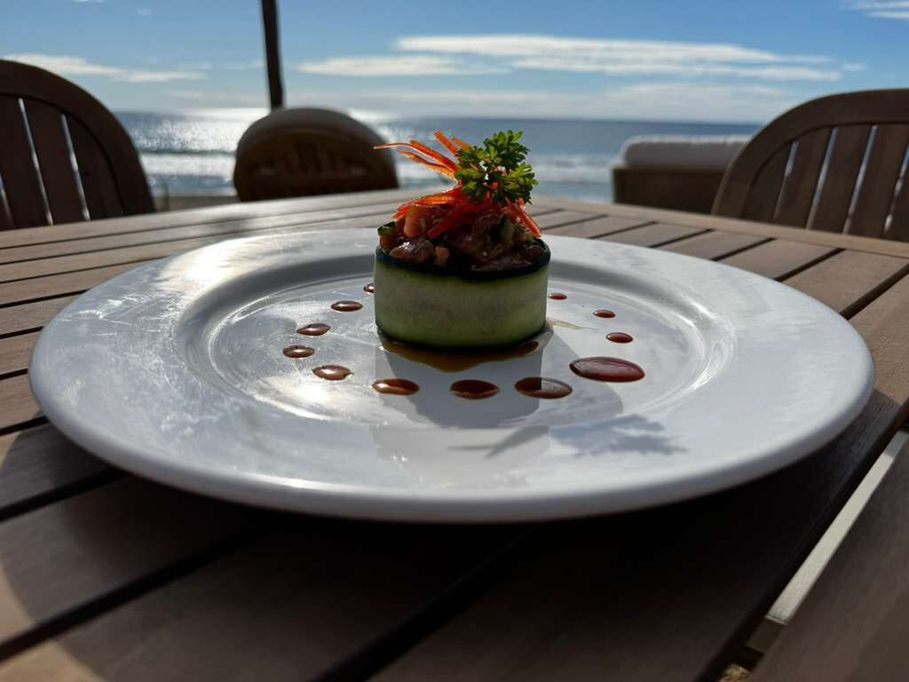 Un plato servido con decoración sobre una mesa con vista al océano.