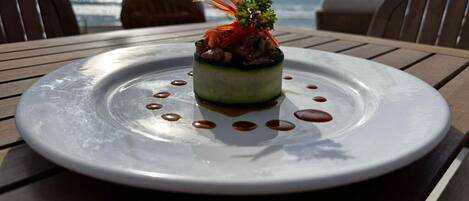Un plato servido con decoración sobre una mesa con vista al océano.