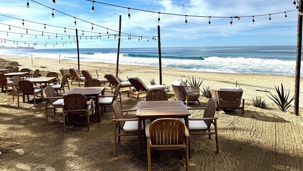 An outdoor seating area with tables and chairs, overlooking the ocean.