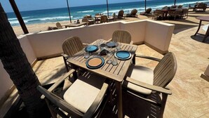 An outdoor dining area with a table set for four, overlooking the beach. - The Cerritos Beach Inn (El Pescadero)