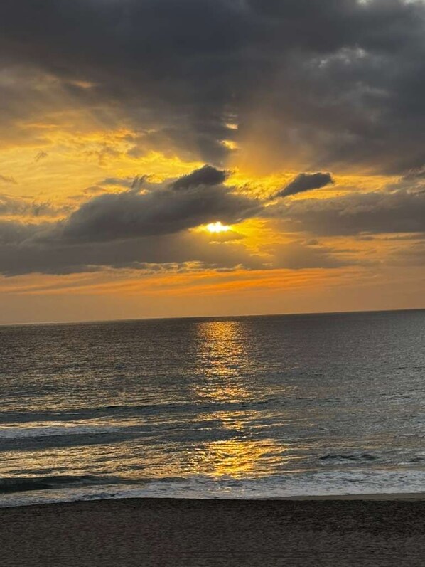 A sunset over the ocean with clouds reflecting on the water.
