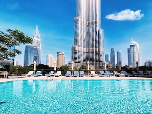 Ein Swimmingpool mit Liegestühlen und einer Stadtkulisse im Hintergrund.