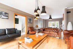 A modern living room with leather sofas, a wooden coffee table, and pendant lighting. - Exquisite Townhouse in Lisbon- Garage & Terrace (Lisboa)