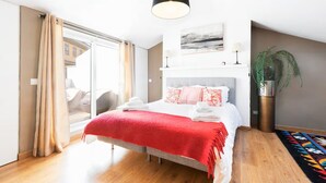 Ein modernes Schlafzimmer mit Bett, großem Fenster, einer Pflanze und Blick auf die Stadt.