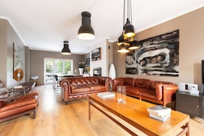A spacious living room with leather sofas, a wooden coffee table, and pendant lighting. - Exquisite Townhouse in Lisbon- Garage & Terrace (Lisboa)