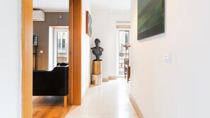 Ein modernes Interieur mit einem schwarzen Sofa, einer Büstenstatue und einem großen abstrakten Gemälde.