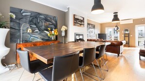 Ein moderner Essbereich mit Holztisch, schwarzen Stühlen und Pendelleuchten.