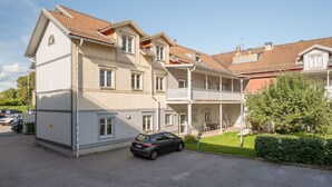 A multi-story residential building with a balcony, a car parked in front, and a well-maintained lawn. - Bright, Modern Apartment in the Heart of Norberg (Norberg)