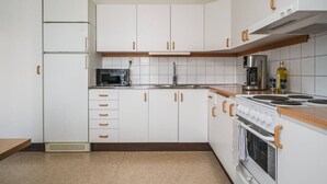 A kitchen with white cabinets, a microwave, a stove, and a sink. - Bright, Modern Apartment in the Heart of Norberg (Norberg)