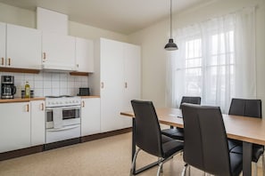 Une cuisine moderne avec des meubles blancs, une cuisinière et un coin repas comprenant une table et des chaises.