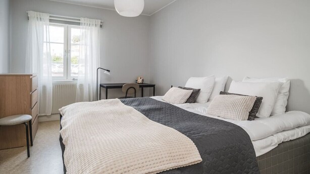 A bedroom with a bed, a desk, and a chair. - Bright, Modern Apartment in the Heart of Norberg (Norberg)