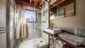 A modern bathroom with a glass shower enclosure, a bathtub, a sink, and a mirror.