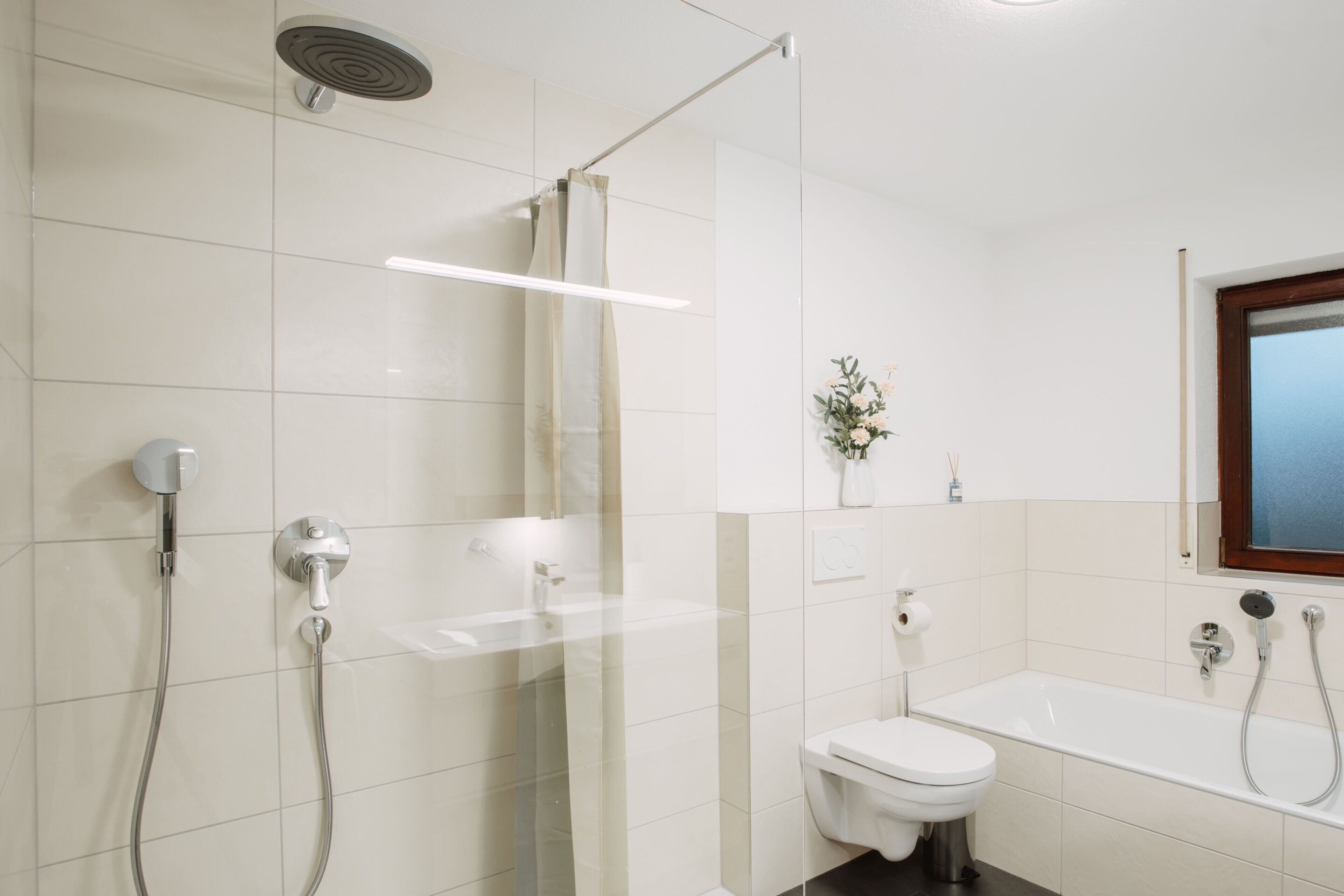 A modern bathroom with a shower, toilet, and bathtub.