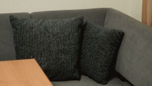 A gray sofa with two dark gray pillows and a wooden table in front.