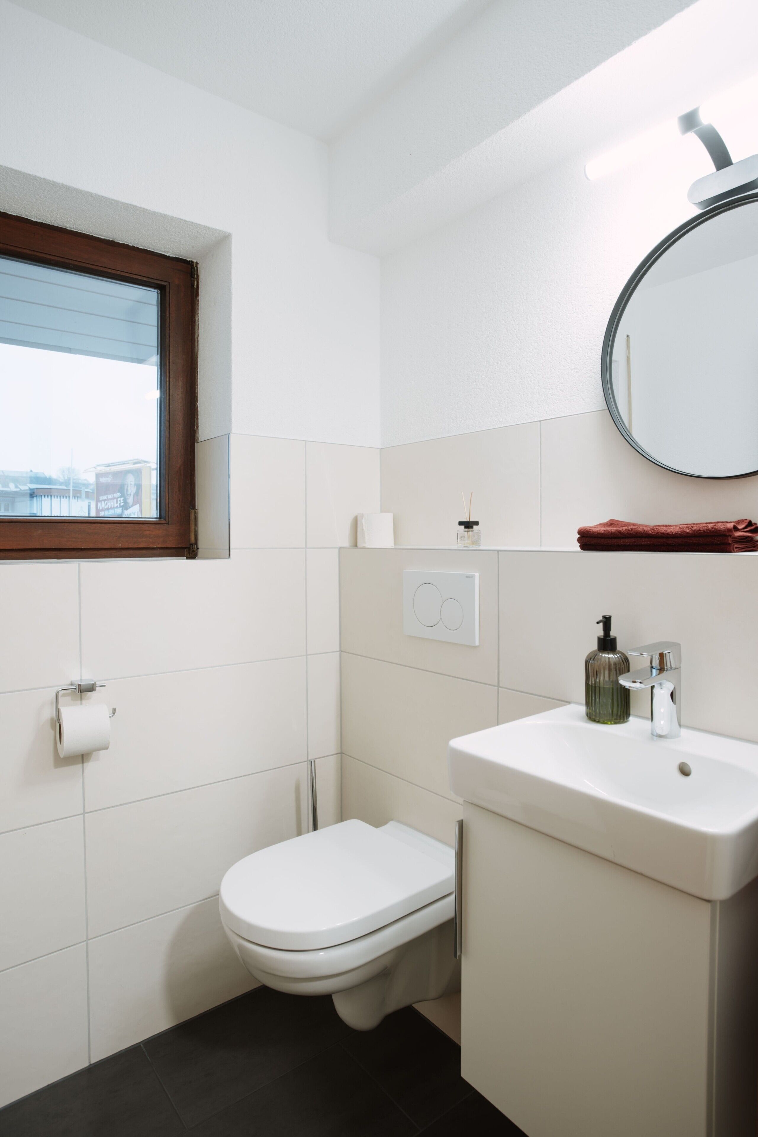 Ein Badezimmer mit Toilette, Waschbecken, Spiegel und Fenster.