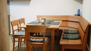 Een eethoek met een houten tafel, vier stoelen en een bank met kussens.
