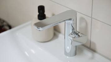 Een wastafel met een chromen kraan en een zeepdispenser.