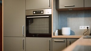 Een moderne keuken met een ingebouwde oven, een magnetron en een koffiezetapparaat op het aanrecht.