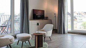 Una sala de estar moderna con televisor, sofá, reposapiés y lámpara de pie.