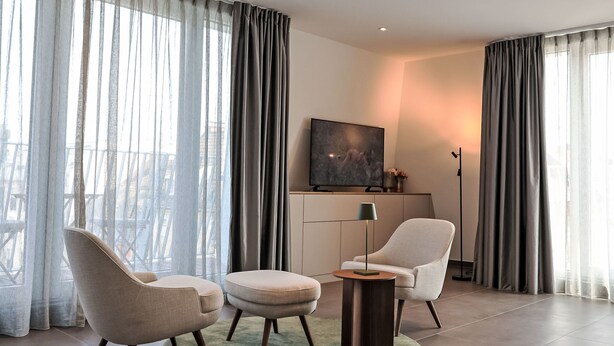 Una sala de estar moderna con dos sillones, una mesa de centro y un televisor sobre un mueble.