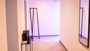 A hallway with a black metal rack, a small table with a sign, and a mirror on the wall. - Munich Finest Apartments 6 by Interhome (Munich)