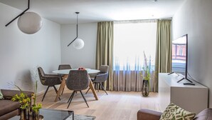 A modern living room with a dining area, a sofa, a coffee table, and a TV. - Munich Finest Apartments 6 by Interhome (Munich)