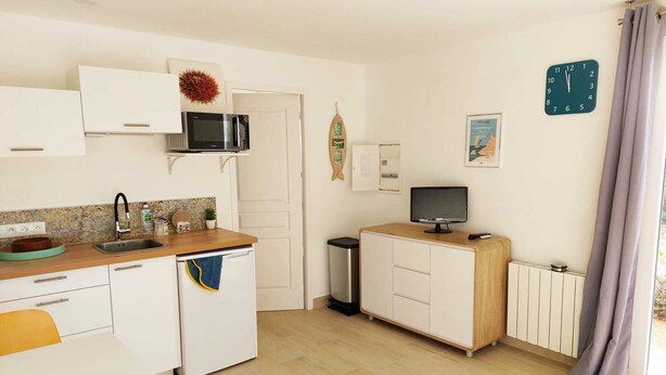 Cocina compacta con microondas, fregadero y una pequeña mesa de comedor.