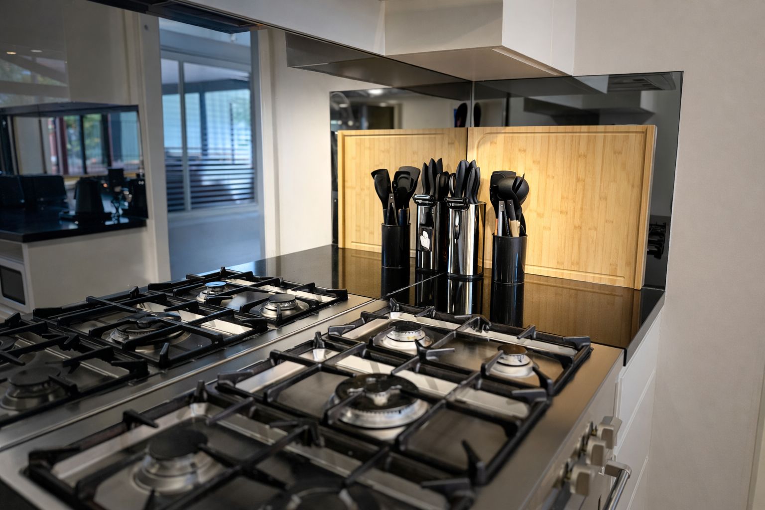 A modern kitchen with a gas stove, wooden cabinets, and a view of the outdoors.