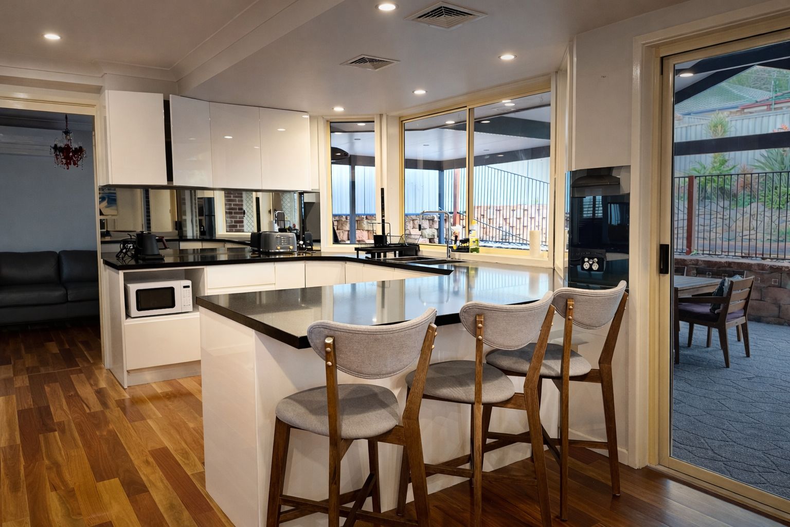 Une cuisine moderne dotée d’un îlot central, de tabourets de bar et offrant une vue sur l’extérieur.