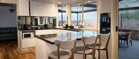 Une cuisine moderne dotée d’un îlot central, de tabourets de bar et offrant une vue sur l’extérieur.