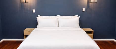 A bedroom with a bed, two bedside tables, and two wall-mounted lights.
