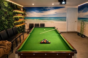A pool table with a green felt surface, surrounded by chairs and a wall with a beach mural. - Resort-Style Family Retreat with Pool & Views (Albion Park)