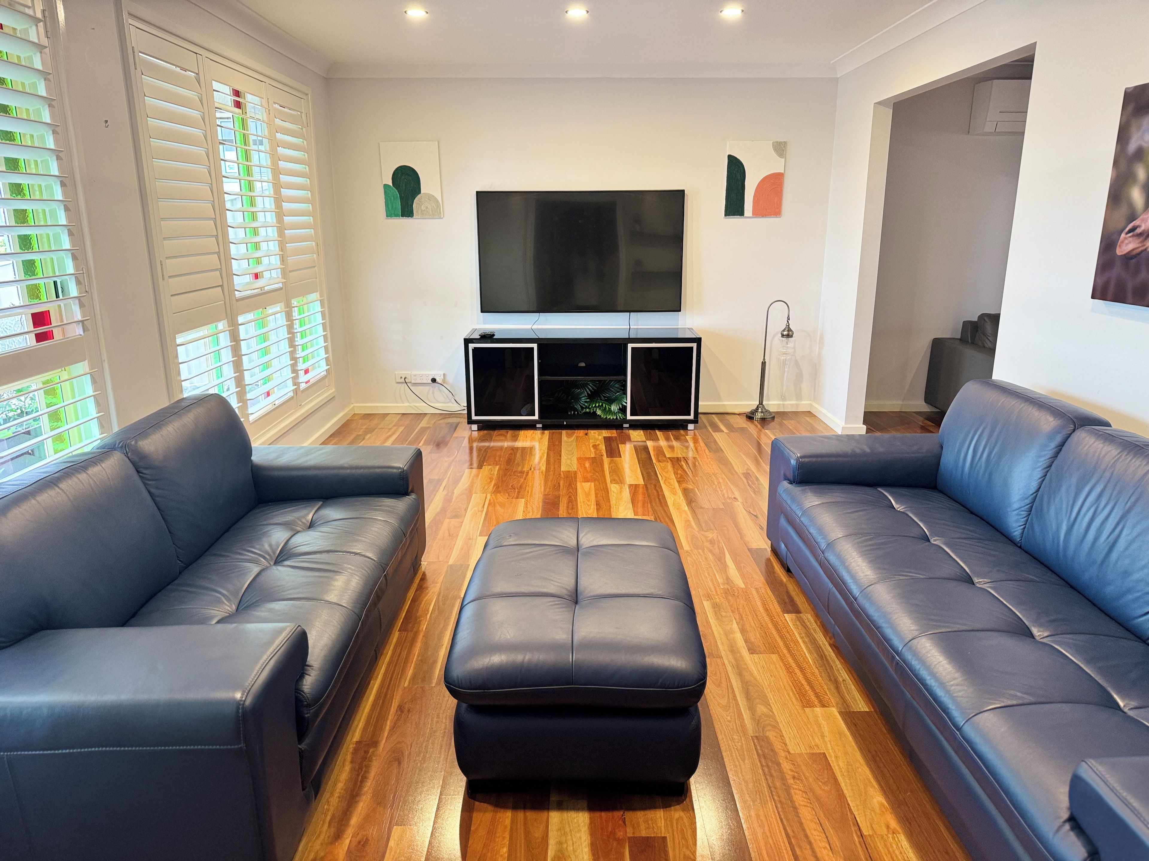 A living room with two sofas, a TV, and a wooden floor.