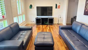 A living room with two sofas, a TV, and a wooden floor.