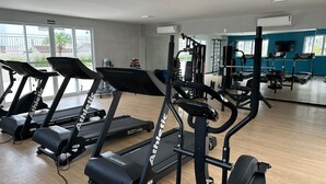 A gym with treadmills, weight machines, and a mirrored wall. - Apto. Novo Perto da Praia da Ponta Negra (Manaus)