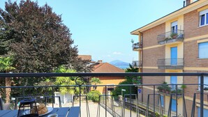 Varanda com mesa posta para o café da manhã, incluindo croissants e café, com vista para uma área residencial e uma montanha ao fundo.
