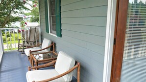 Een veranda met vier rieten schommelstoelen en een glazen tafel.