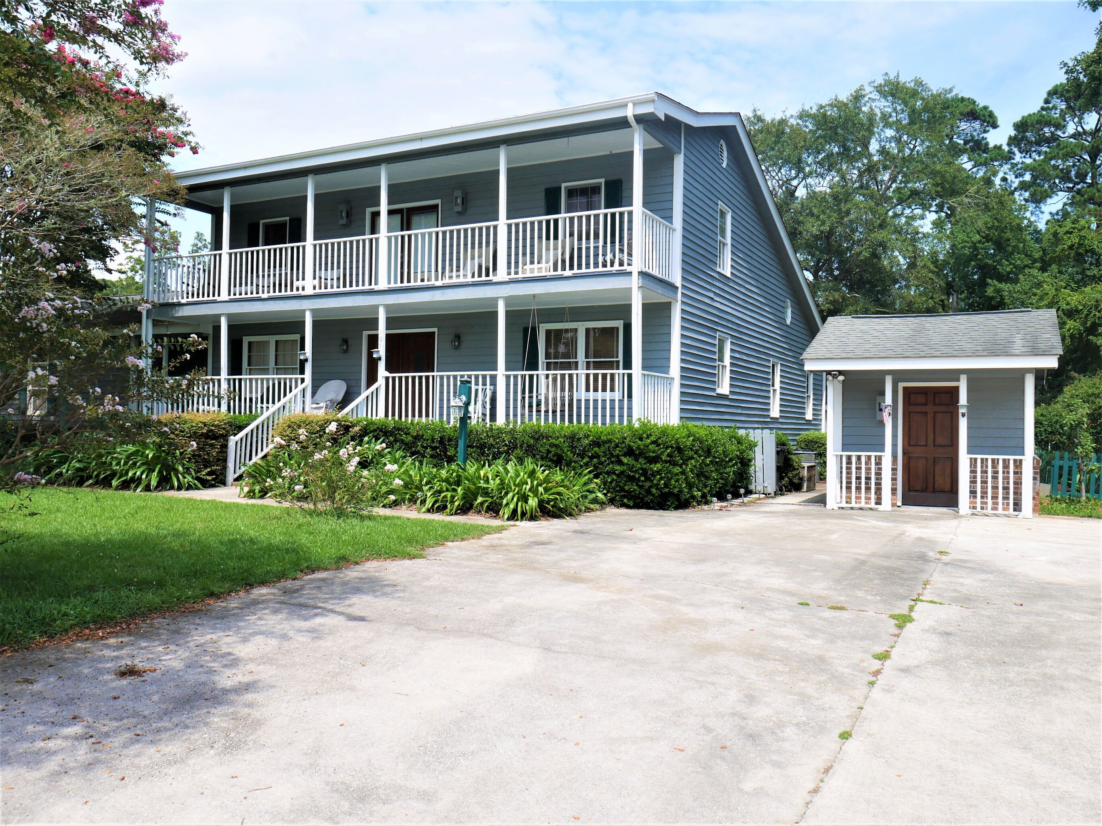 A two-story house with a front porch, a small attached garage, and a well-maintained lawn.